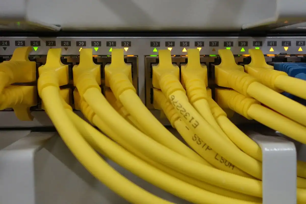 Cabluri de rețea galbene conectate în porturile unui switch dintr-un dulap de comunicații