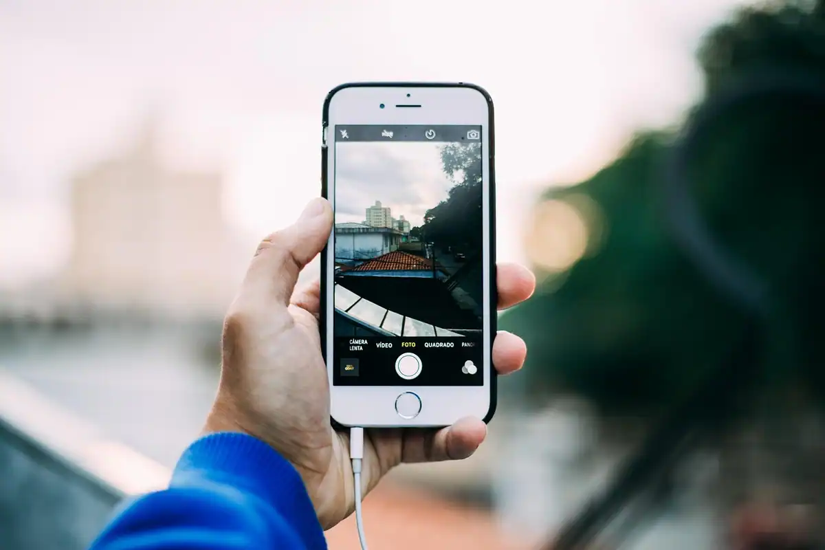 Mână care ține un smartphone și fotografiază o stradă din oraș