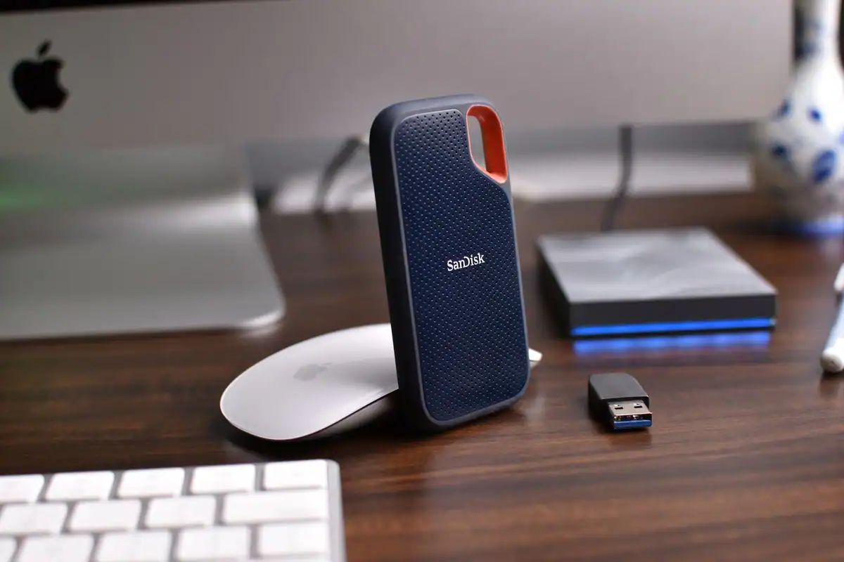 Birou cu hard-diskuri externe, un mouse și un stick USB, văzute de aproape