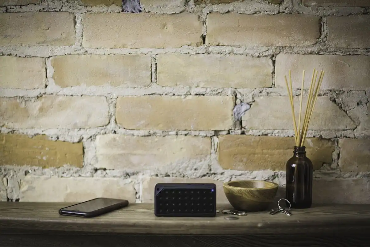 Boxă Bluetooth portabilă neagră așezată pe o masă din lemn, într-un interior de casă