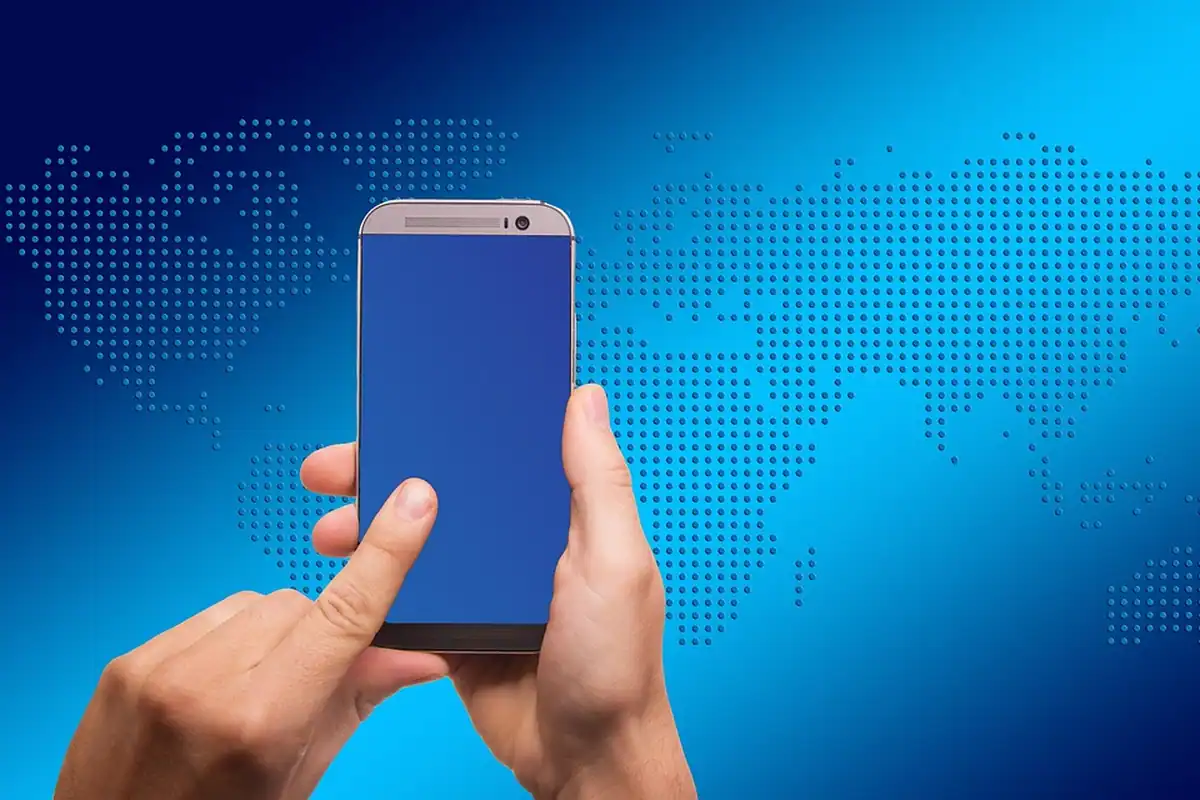 Mână care atinge un smartphone pe fundalul unei hărți a lumii din puncte
