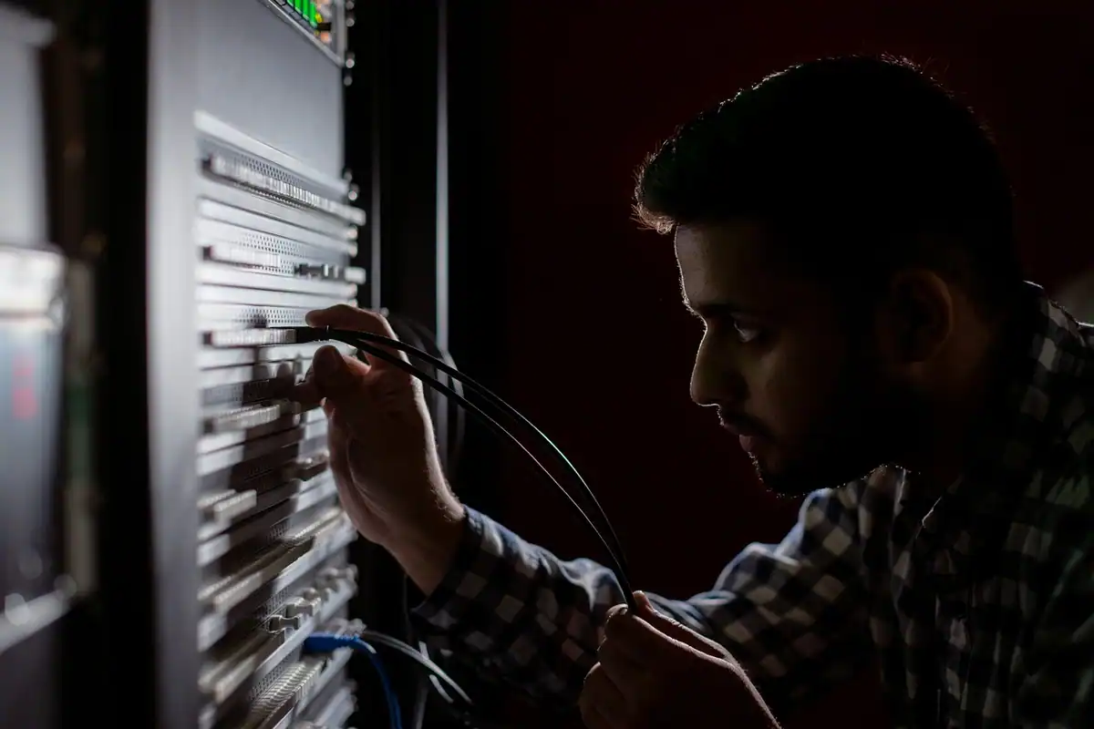 Tehnician care conectează cabluri la echipamentele dintr-un rack de servere
