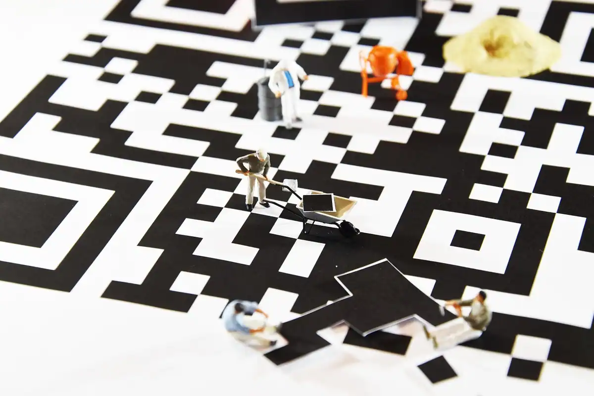 Figurine de muncitori care repară un cod QR alb-negru, cu un modul desprins