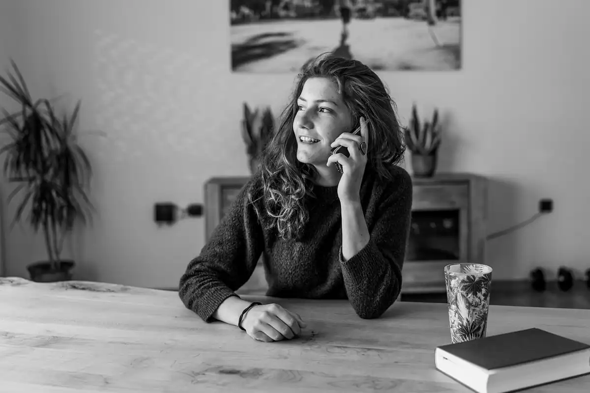 Femeie care vorbește la telefon la o masă, într-o fotografie alb-negru
