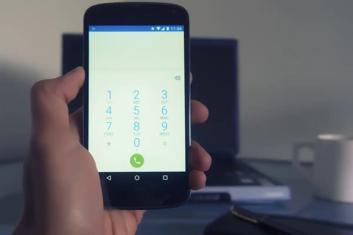 Telefon așezat pe un încărcător wireless rotund de pe un birou, lângă o cană de cafea