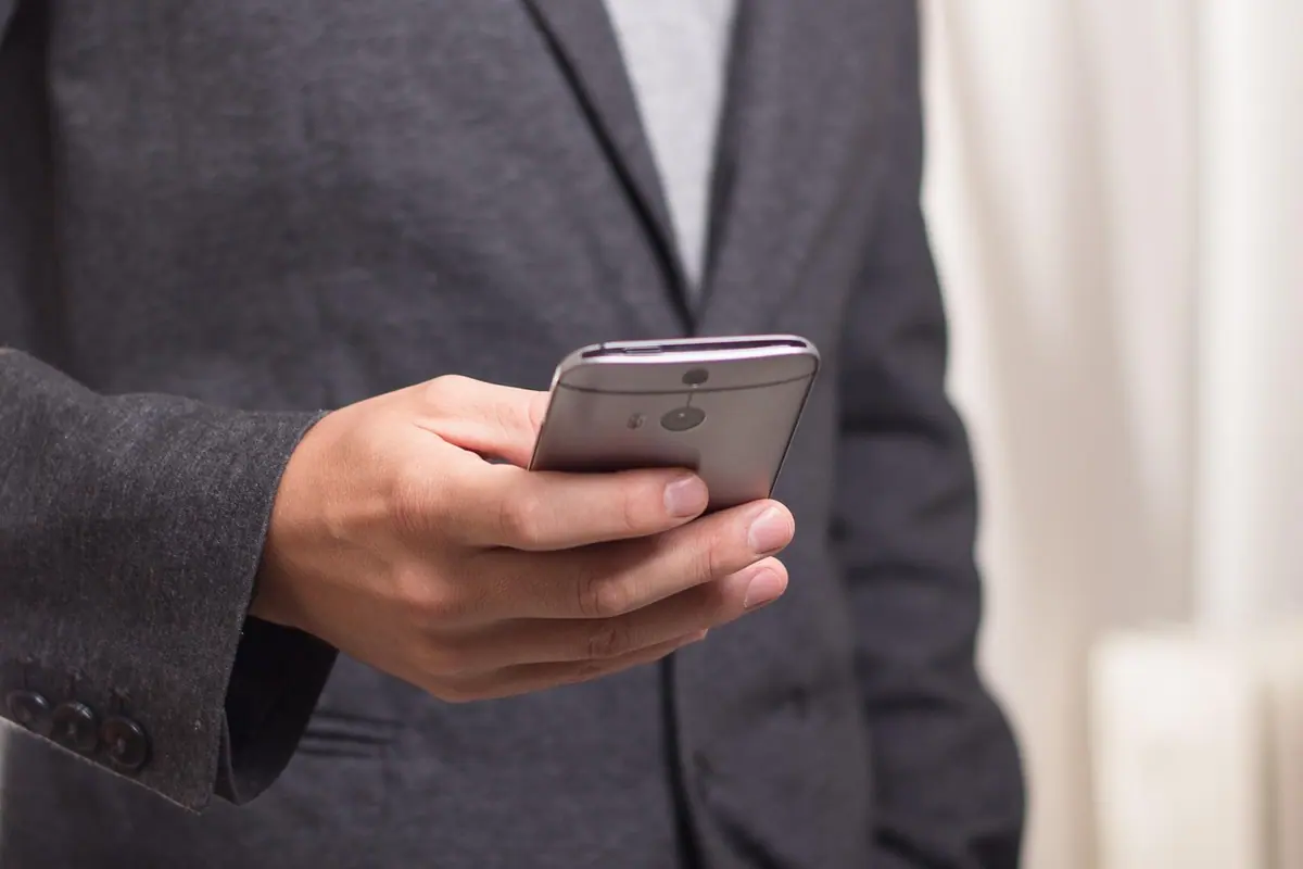 Bărbat la costum care ține un telefon, pregătit să răspundă unui apel