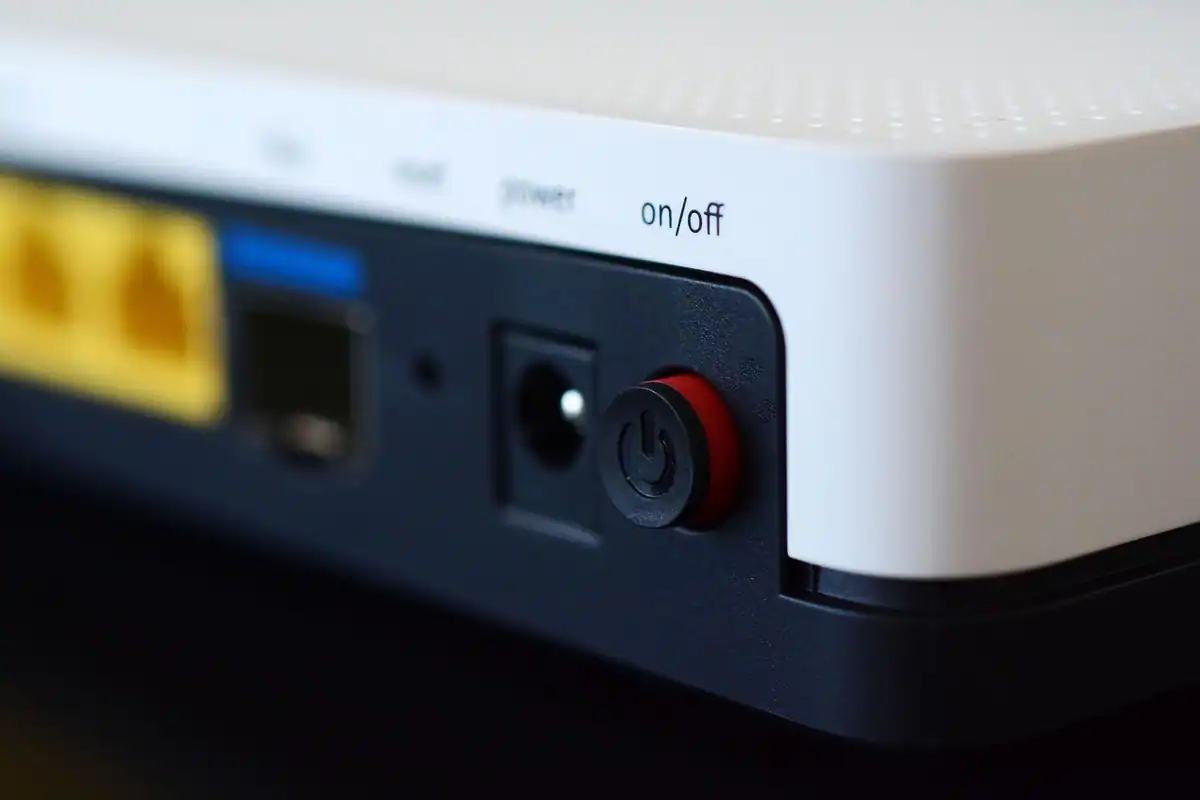 Router și modem așezate pe un birou, cu butonul de pornire vizibil pe carcasă