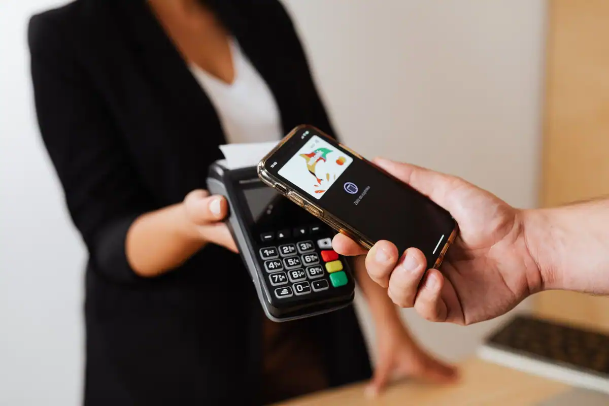 Client care apropie telefonul de terminalul de plată ținut de o vânzătoare