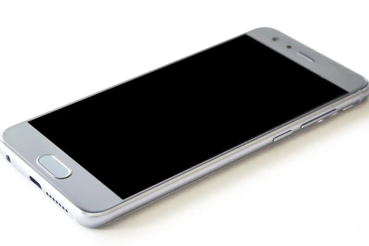 Smartphone argintiu cu senzor de amprentă, așezat pe o suprafață albă