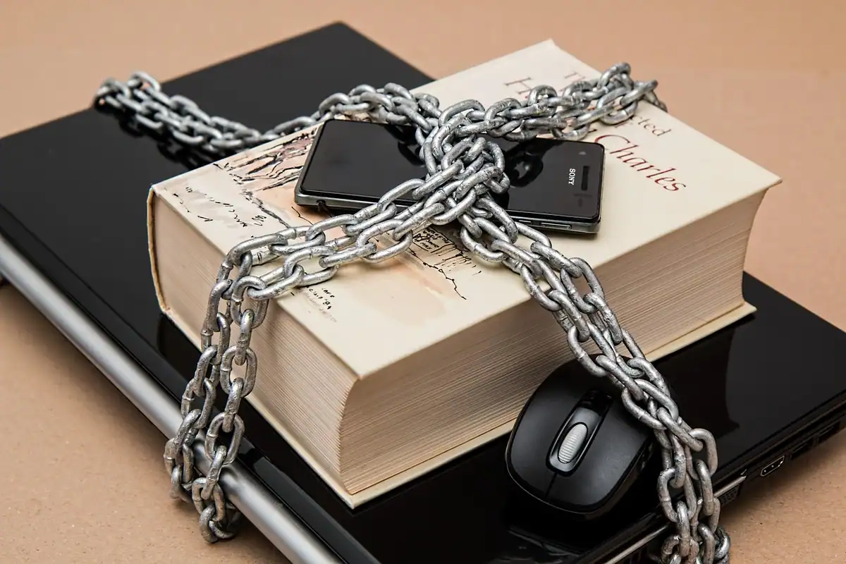 Smartphone cu setările de confidențialitate pe ecran, lângă un laptop și un caiet pe birou