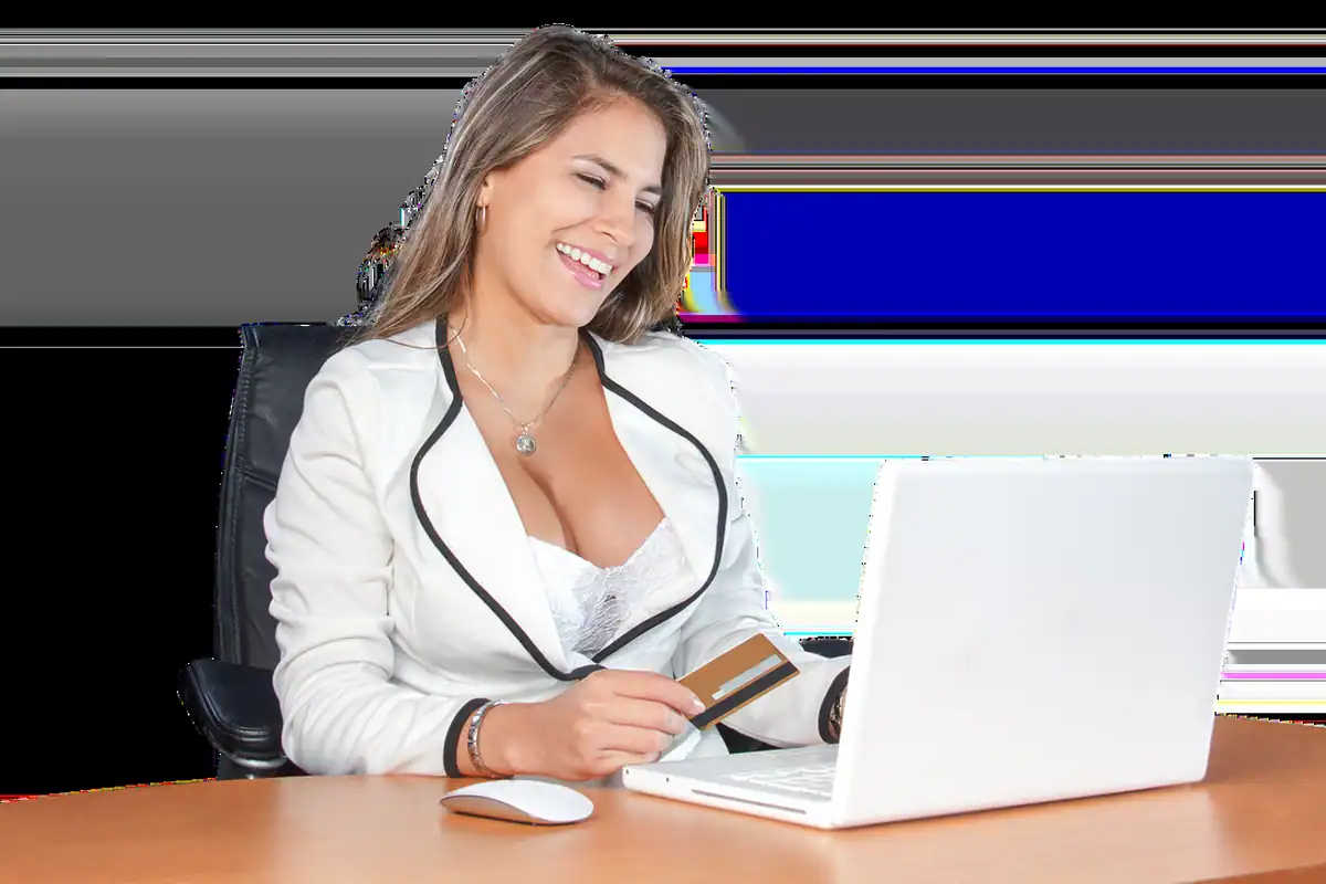 Femeie zâmbitoare lucrând la un laptop, cu un card bancar alături, pregătită să plătească online