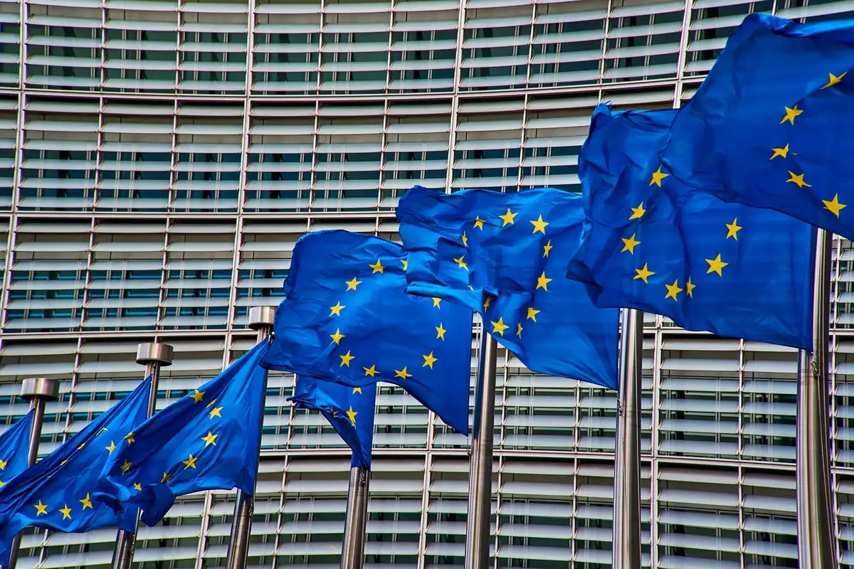 Steaguri ale Uniunii Europene fluturând în fața unei clădiri cu multe ferestre