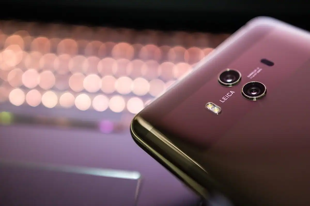 Obiectiv de cameră al unui smartphone văzut de aproape, cu reflexii pe lentilă și fundal estompat