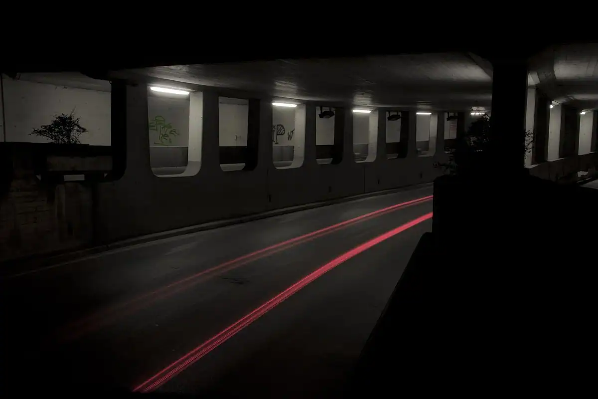 Pasaj subteran de beton luminat, fotografiat noaptea cu expunere lungă, fără mașini pe drum