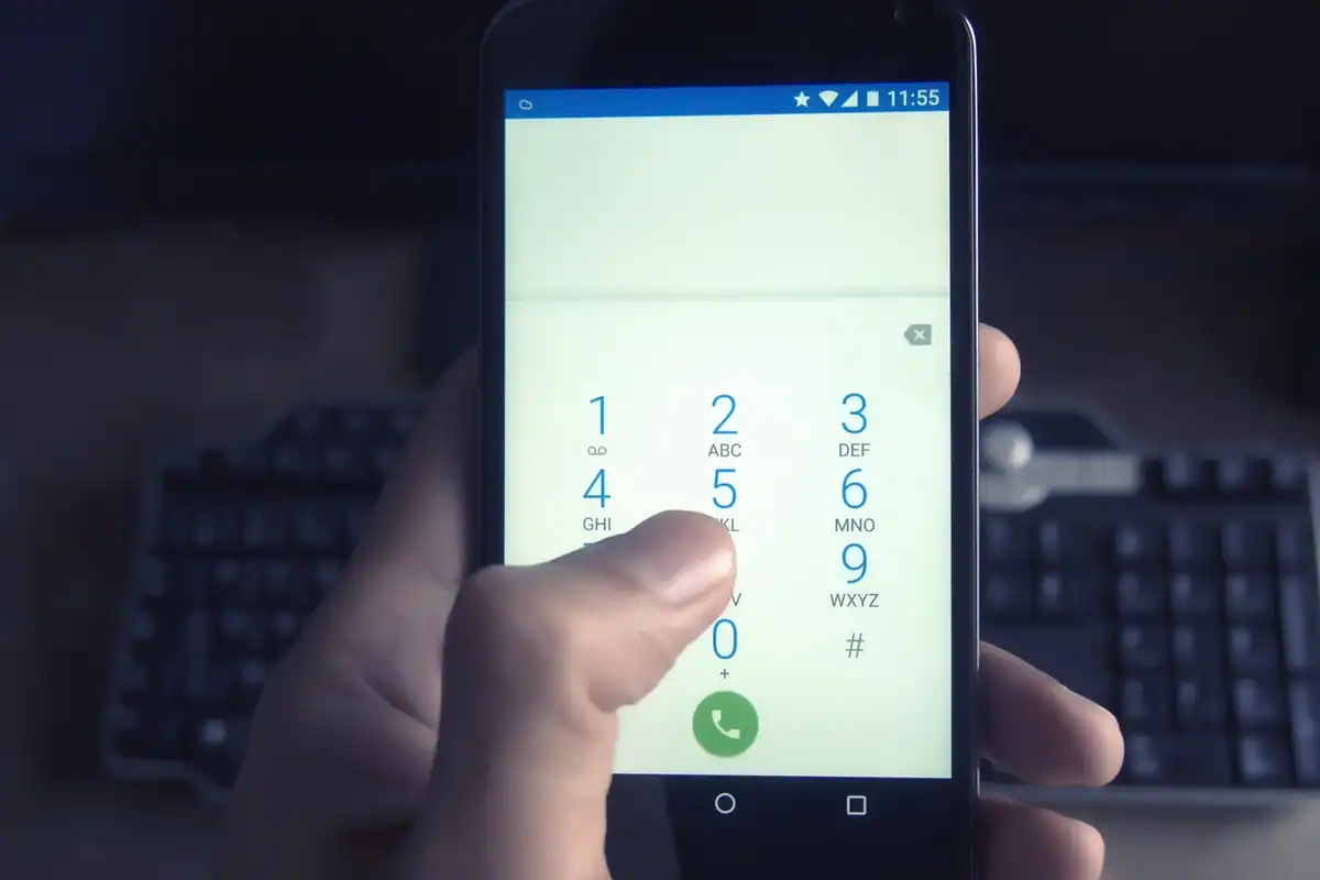 Smartphone ținut în mână, cu un apel de la un număr necunoscut afișat pe ecran