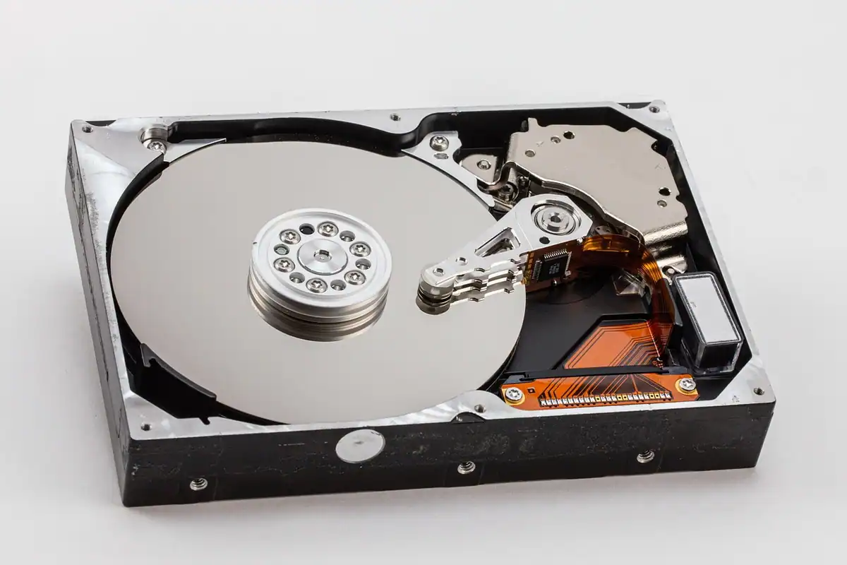Hard disk desfăcut cu platanul și brațul de citire, pe fundal alb